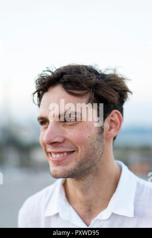 Portrait of smiling young man with tousled hair outdoors Stock Photo