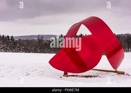 Whales Tail, a red aluminum sculpture by Miriam Nelson, punctuates winter landscape at the Stone Quarry Hill Art Park. Stock Photo