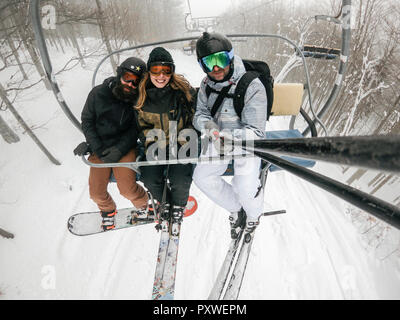 Italy, Modena, Cimone, portrait of happy friends taking a selfie in a ski lift Stock Photo
