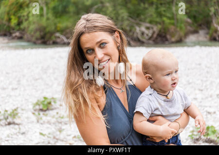 Portrait of smiling mother holding baby boy outdoors in nature Stock Photo