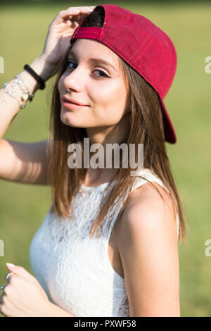 Portrait of smiling young woman wearing baseball cap outdoors Stock Photo