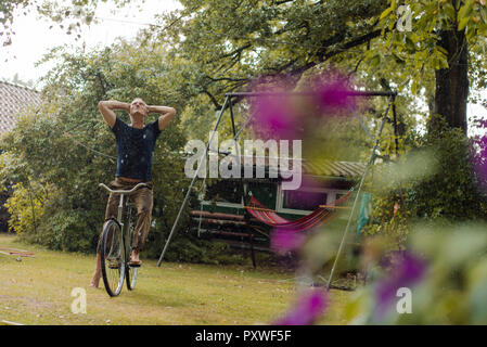Mature man with bicycle enjoying summer rain in garden Stock Photo