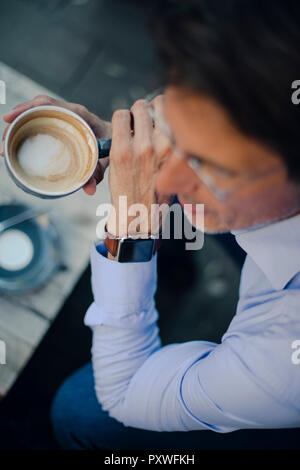 Mature businessman sitting in coffee shop, wearing smart watch Stock Photo