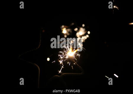 Sparklers in the night with sparks flying in the dark for bonfire night or New Years eve Stock Photo