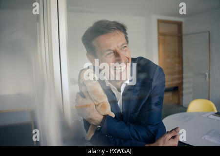 Successful businessman holding cuddly toy Stock Photo
