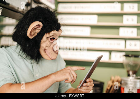 Man wearing monkey mask, using digital tablet Stock Photo