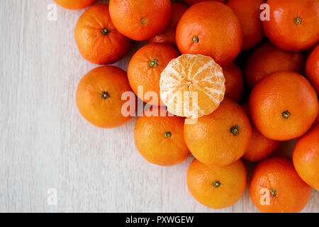 Background many tangerines and one without peel. Stock Photo