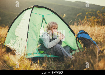 Senior woman is camping in mountain. Active retirement. Stock Photo