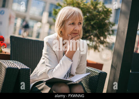 Senior businesswoman is sitting in cafe and making business plans. Stock Photo