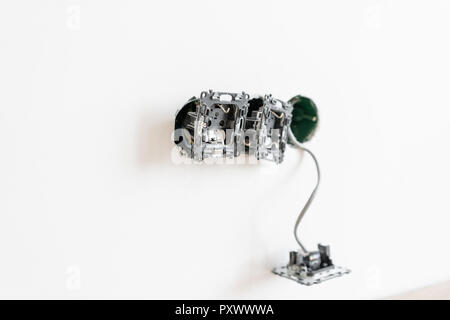 electrician connects the sockets to the electrical wires on wall in White room. Screwdriver, close-up electrician hands. Stock Photo