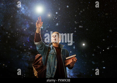 guy with the books reaches for the stars, the concept of imagination. Dreams of other worlds, fantasy Stock Photo