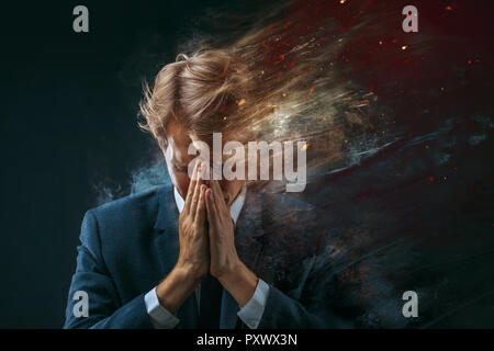 broken businessman. Stress at work, concept. man in a business suit grabbed his head and sprayed into pieces. dark background Stock Photo