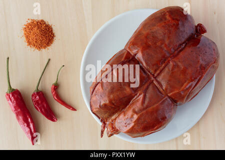 Red chili peppers, ground chili and Calabrian 'nduja salumi from southern Italy, top down view on wood background. Stock Photo