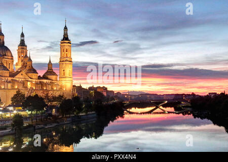 A landscape of Pilar Cathedral and Santiago Bridge reflecting in the Ebro river at sunset, after a storm, in a cloudy autumn, in Zaragoza, Spain Stock Photo