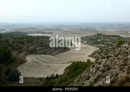 A landscape of cultivated ploughed crop fields at sunset, with bushes and pine trees, in the small rural town of Leciñena, in Aragon region, Spain Stock Photo