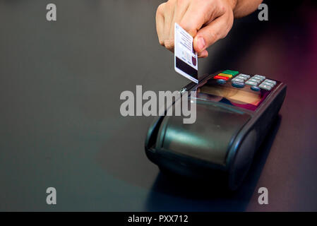 Female hand with credit card and bank terminal, Card machine or pos terminal with inserted blank white credit card isolated on black background Stock Photo