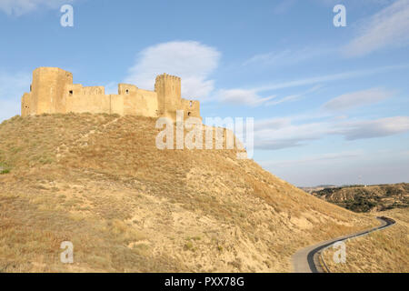 A landscape of the medieval abandoned Montearagon castle, placed over a hill among tilled crop fields, in a summer afternoon, in Aragon region, Spain Stock Photo