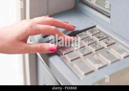 Finger pressing password number on ATM machine. Woman using banking machine. Close up Stock Photo