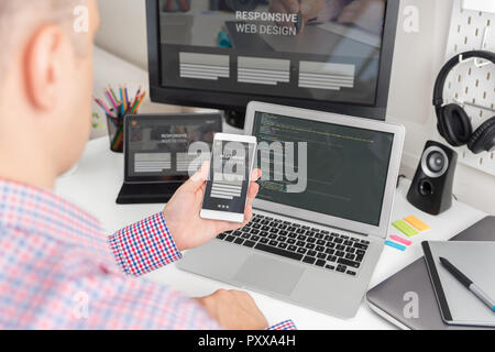 Designer working on responsive web design project. Web developer and programmer working in office with modern devices on desk Stock Photo