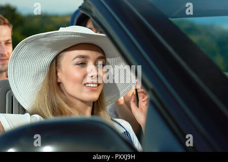 Gorgeous blonde model sitting in cabriolet and looking away. Charming young woman smiling and posing while going for a drive. Concept of convertible automobile and journey. Stock Photo