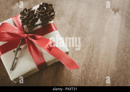 Vintage Christmas background. Kraft boxes with gifts, tied with red ribbons and pine cones in rustic style. Selective Focus. Copy space. Vintage Toned Stock Photo
