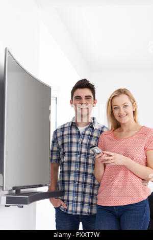 Portrait Of Young Couple With New Curved Screen Television At Home Stock Photo