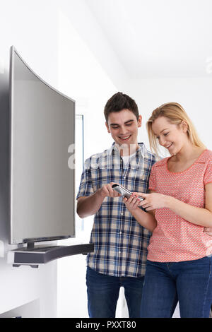 Young Couple With New Curved Screen Television At Home Stock Photo