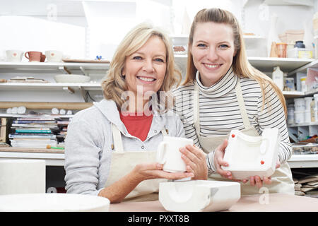 Portrait Of Teacher With Mature Woman Making Mug In Pottery Class Stock Photo