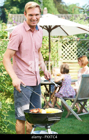 Portrait Of Father Cooking Barbeque For Family In Garden At Home Stock Photo