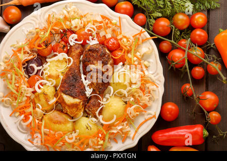 Portion of roasted chicken legs with vegetables on white  plate Stock Photo