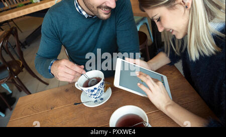 Young attractive couple having fun with tablet in cafe Stock Photo