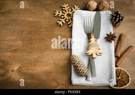 Vintage or rustic christmas table setting from above. Cutlery on linen napkin on rustic wooden background - country style. Selective focus, space for  Stock Photo