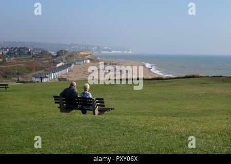elderly couple enjoying the sunshine from cliff top  at Bexhill with a view towards Hastings, East Sussex, UK Stock Photo