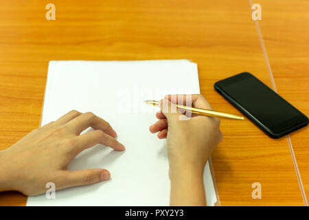 Hand holding pen to taking notes on paperwork at conference meeting room. Stock Photo