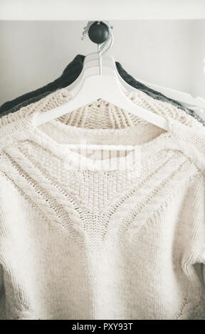 Row of warm knitted sweaters hanging on hangers Stock Photo