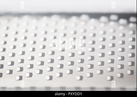Repeating background of squares created from a close-up view of a metal grater found in the kitchen. Stock Photo