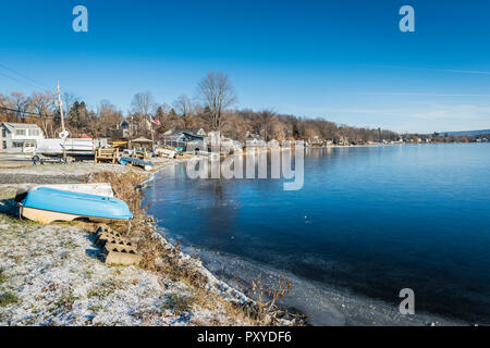 Snow covers shore by freezing water as boats are put up for the winter on Snyders Lake in Upstate New York. Stock Photo