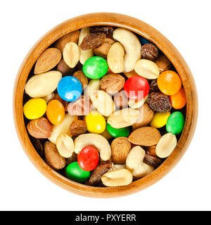 Trail mix in wooden bowl. Snack mix. Almonds, cashews, peanuts, hazelnuts, raisins and colorful chocolate candies. Food to be taken along hikes. Stock Photo