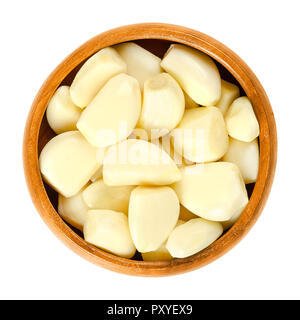 Peeled garlic cloves in wooden bowl. Allium sativum, with its pungent flavor is used as a seasoning or condiment and also in medicine. Stock Photo