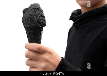 A boy holding black ice cream in black wafer cone. White background. Stock Photo