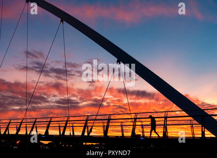 Stockton on Tees, north east England, United Kingdom. 24th Oct, 2018. Weather: People crossing the Infinity bridge over the river Tees in Stockton are treated to a spectacular sunset on Wednesday. Credit: ALAN DAWSON/Alamy Live News Stock Photo