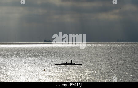 Worthing UK 25th October 2018 - Rowers enjoy the calm conditions with dark skies in the distance out on the sea at Worthing today as the weather is forecast to change dramatically over the next few days with a cold spell set to spread across the UK Credit: Simon Dack/Alamy Live News Stock Photo
