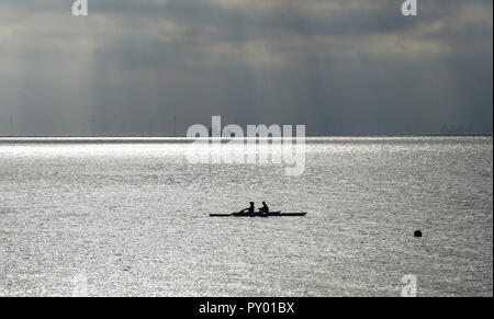 Worthing UK 25th October 2018 - Rowers enjoy the calm conditions with dark skies in the distance out on the sea at Worthing today as the weather is forecast to change dramatically over the next few days with a cold spell set to spread across the UK Credit: Simon Dack/Alamy Live News Stock Photo