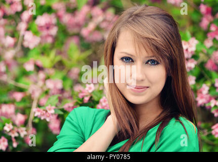 beautiful brunette posing against spring flowers Stock Photo