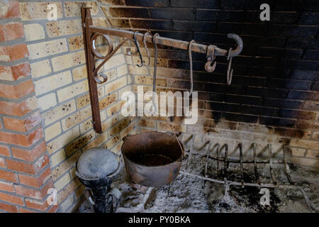 Antique rustic kitchen fireplace with old cooking utensils. Interior of home at Chestnut Square Historic Village, McKinney Texas. Stock Photo