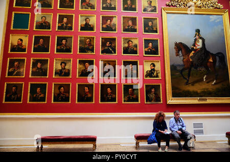 Two people seated in the Portrait Gallery of Heroes from the 1812. War Portrait Gallery of war heroes. The State Hermitage Museum. Saint Petersburg, N Stock Photo