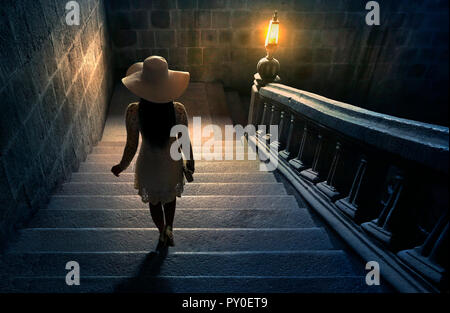 Woman in white lace dress and hat walking down stairs on colonial staircase in San Agustin Church, Manila, Philippines Stock Photo