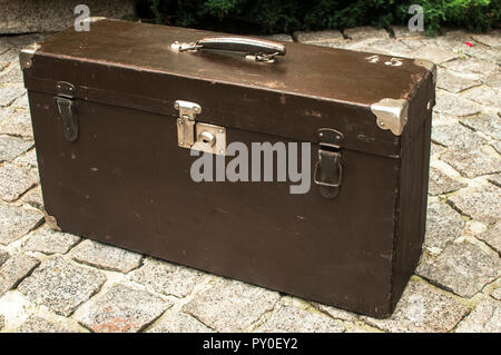 Old used weathered vintage grunge suitcase on stone pavement closeup in house backyard Stock Photo