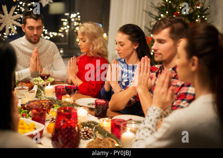 friends having home christmas dinner and praying Stock Photo