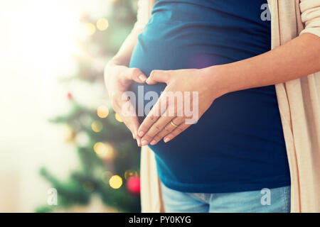 close up of pregnant woman making heart on belly Stock Photo